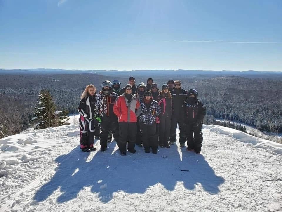 A group of people standing on top of a snow covered slope.