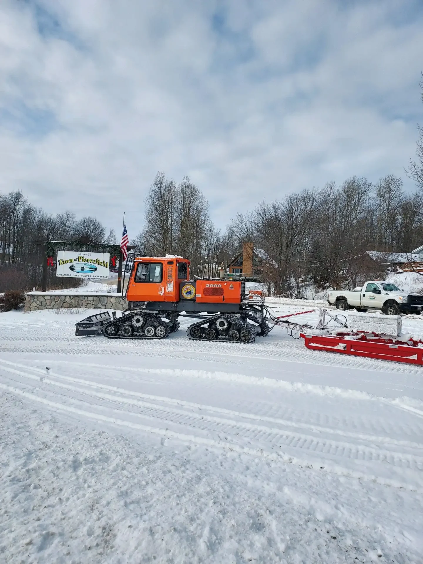 A snow plow truck is parked in the snow.
