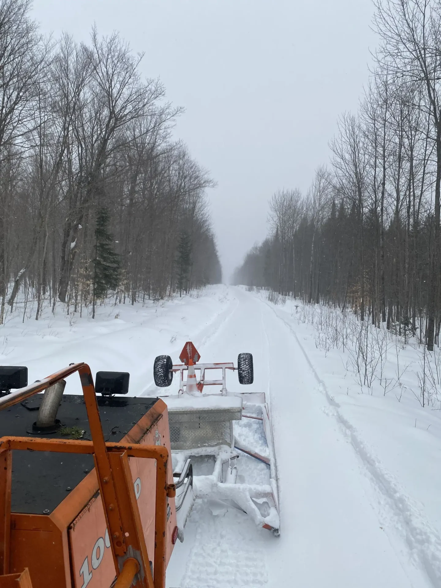 A snow plow driving down the road in winter.