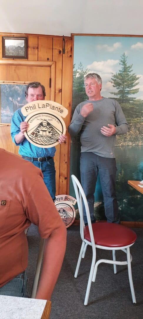 Two men, one holding a circular wooden plaque with 